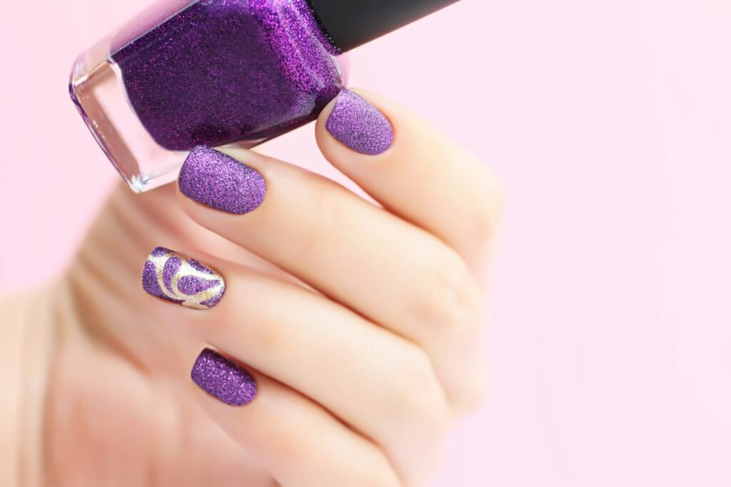 Sand textured manicure.Woman shows her nails,holding nail lacquer in the hand.